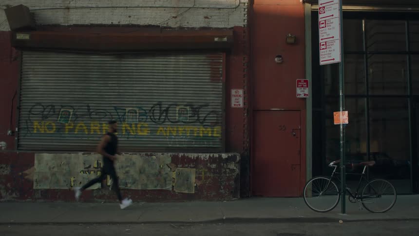 A man jogs by a city building with graffiti