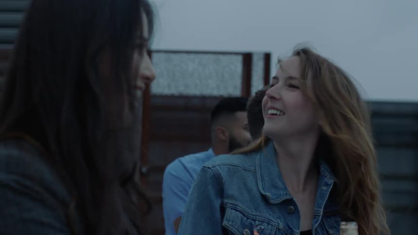 Two women talk and laugh as they drink