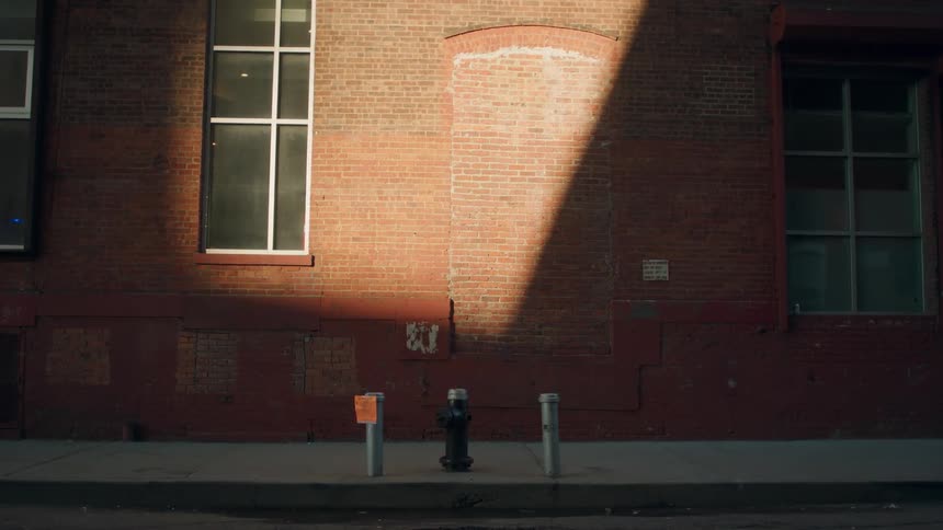 Man runs on a sidewalk next to a red brick building