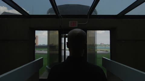A woman is walking toward the exit of a modern building
