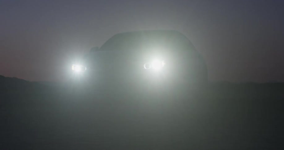 A car drives in a desert landscape at dusk