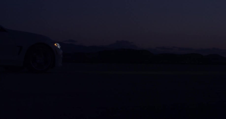 A vehicle drives through the desert at night