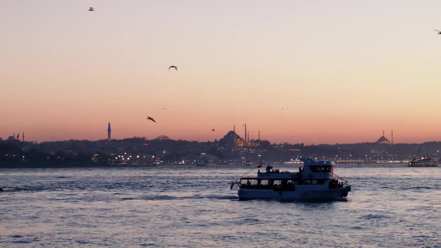 A boat sails in the water at sunset