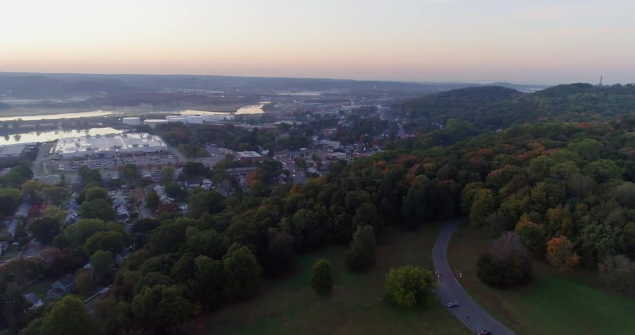 A winding road goes into the forest by a town on the other side