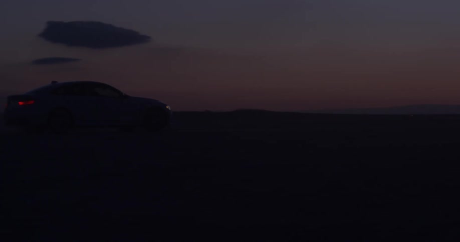 A car drives down the road after sunset
