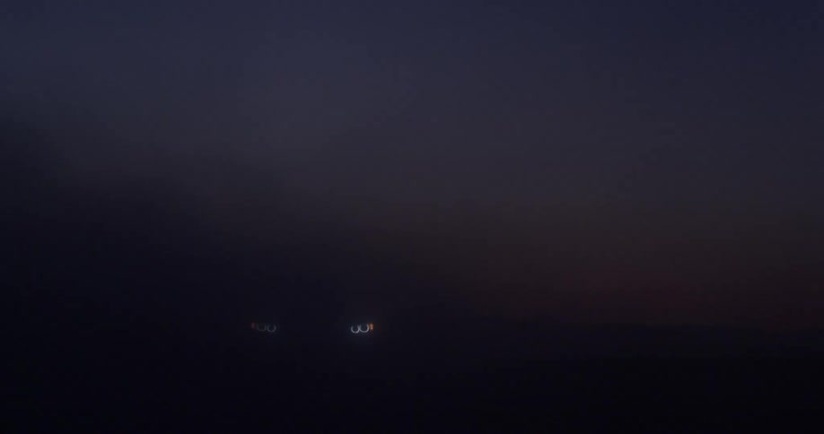 A car drives through mist at night