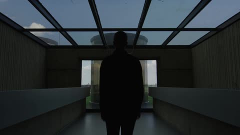 Man standing in an office building looking out a window