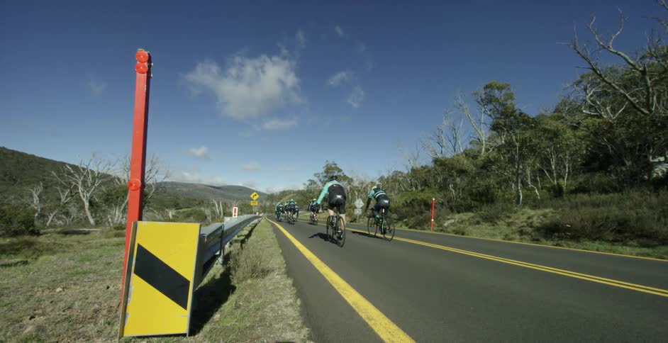 Many bicyclists ride down a paved road
