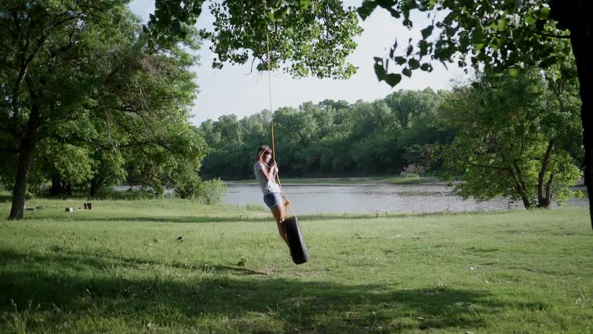 A girl is swinging on a tire hanging from a tree