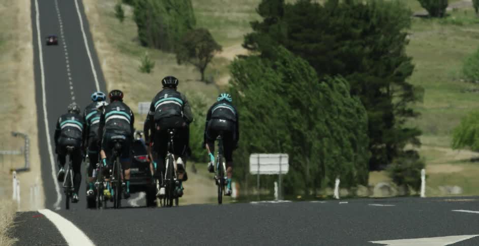 Bicyclists travel down a hill on a highway