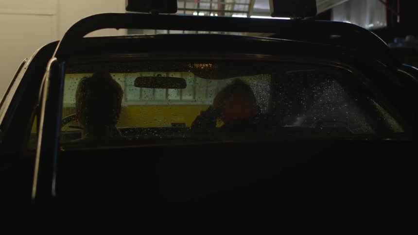 Two men sit in a car at night