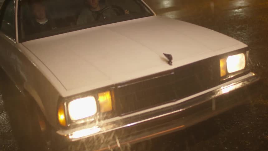 Two men sit in a car as it rains