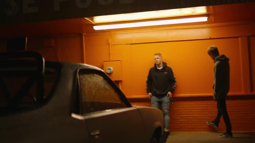 Two men stand next to a food mart at night