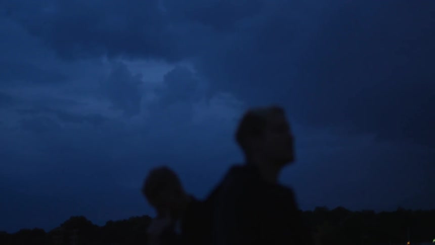 Two men smoke outside at night