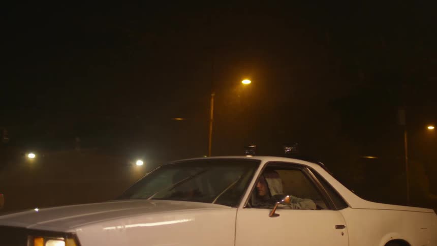 Two men sit in a car in the rain