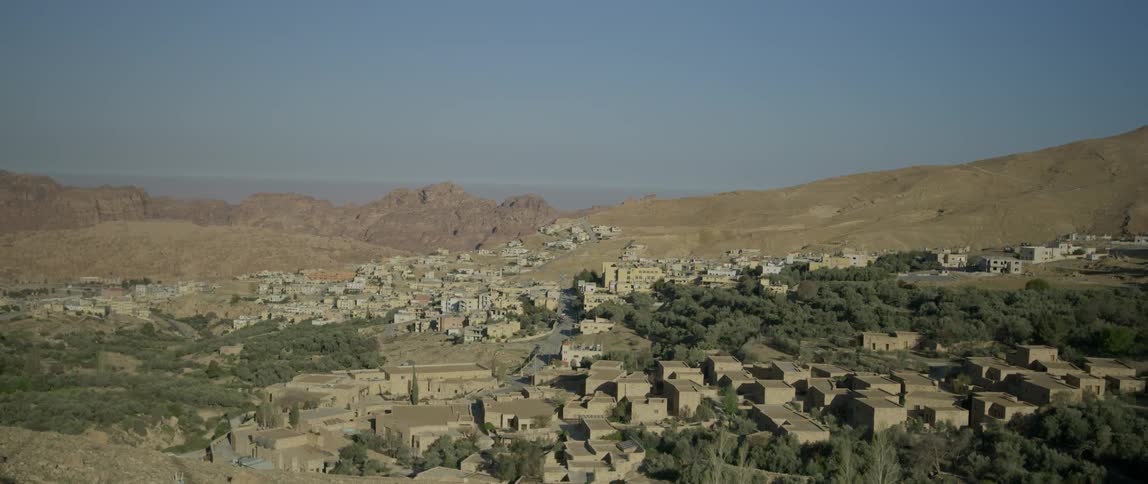 The small town has mountains behind it on a sunny day