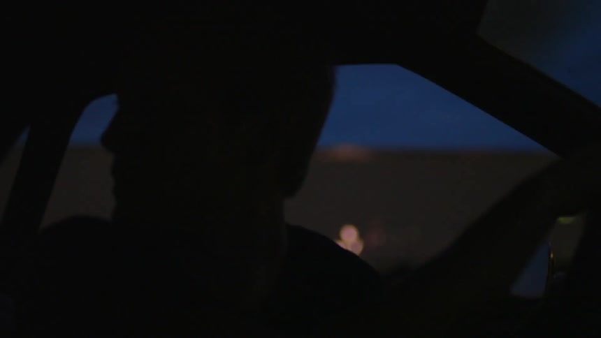 A man backs up a car at night
