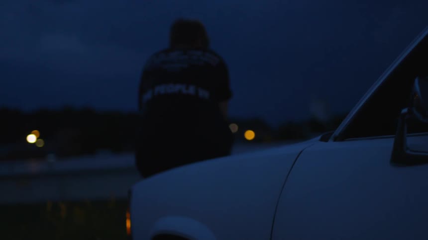 A man is sitting on his car at dawn