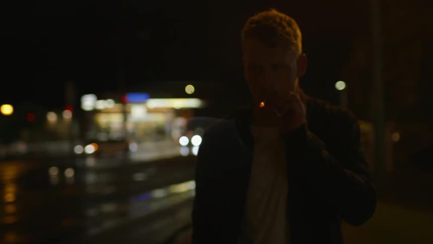 A man smokes as he walks at night