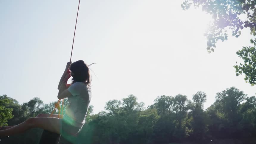 A young woman swings from a tire swing