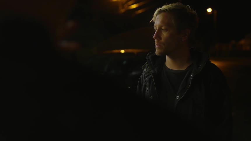 A man smokes a cigarette outside at night