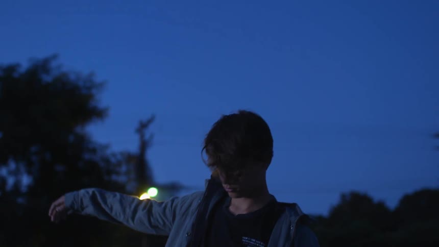 A young man twirls outside at night