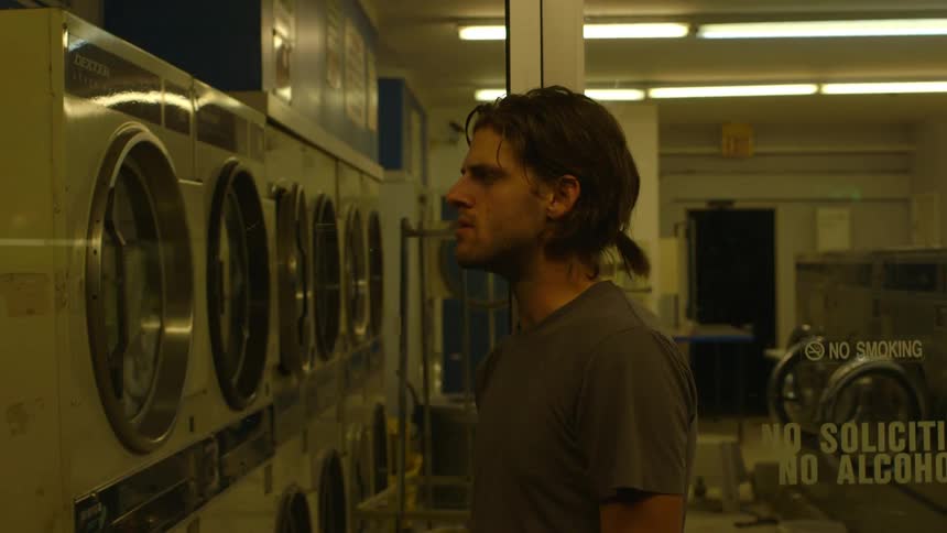 A man smokes a cigarette in a laundromat
