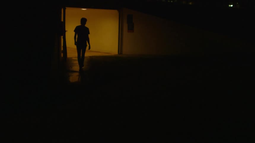 A man walks down a dark sidewalk