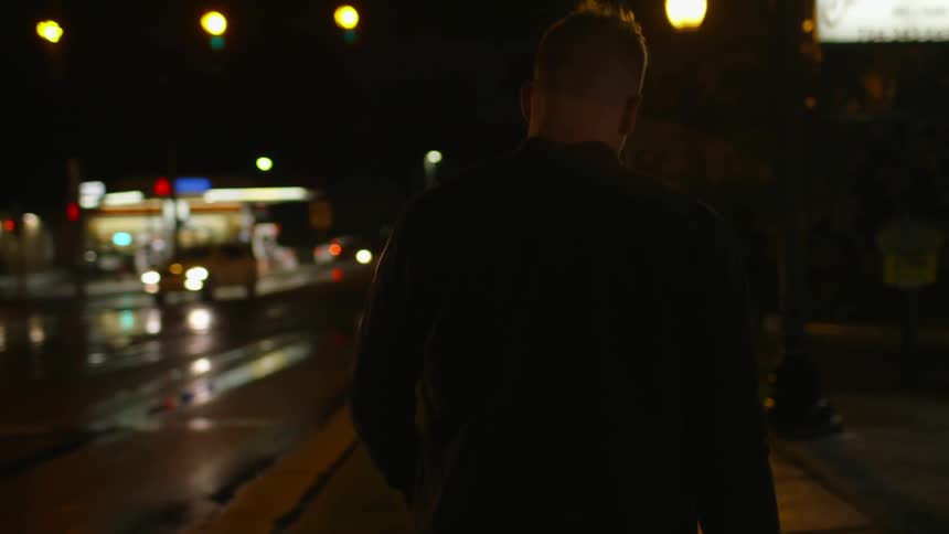 A man smokes as he walks at night