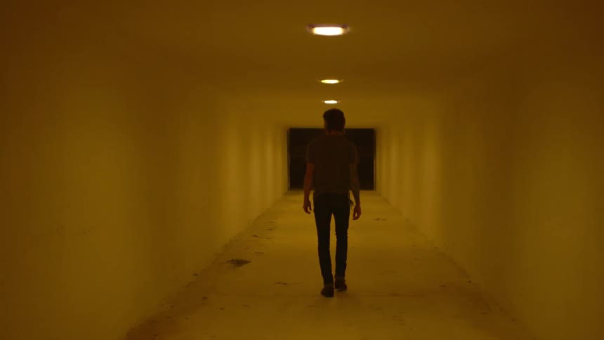 Man walks through a lighted corridor