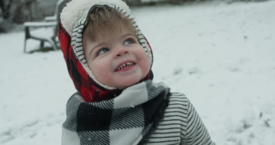 A small child is filmed close up playing in the snow