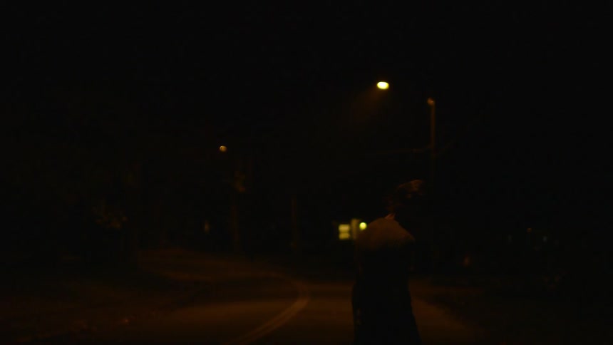 A man walks on a dark street at night