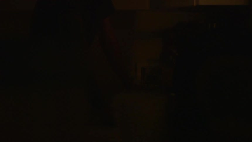 A man stands in a dark kitchen