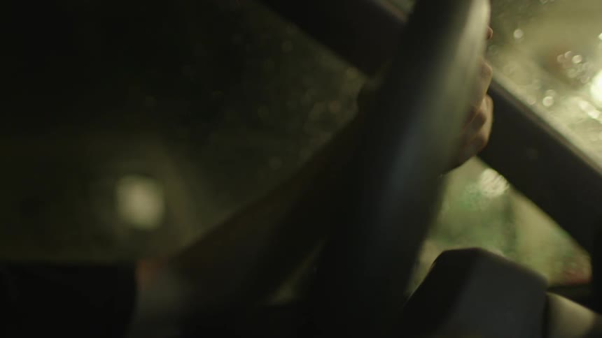 A driver grips a steering wheel at night
