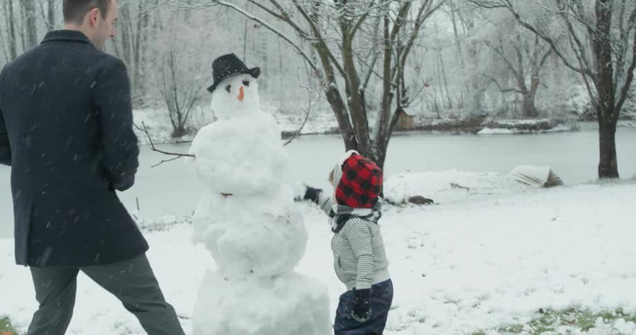 Young child puts snow on a snowman
