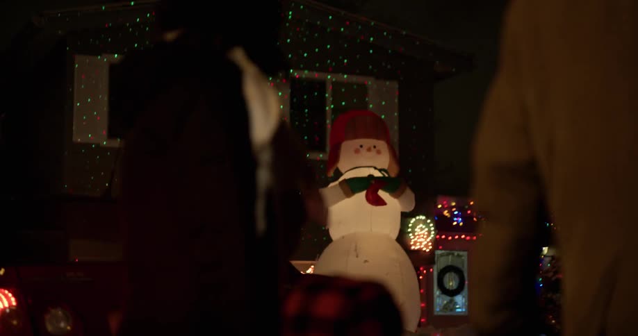 A child and parents walks past viewing the christmas decorations on a home