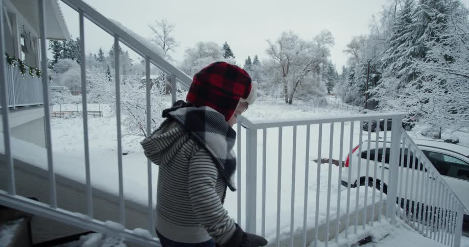 A toddler walks down snowy stairs