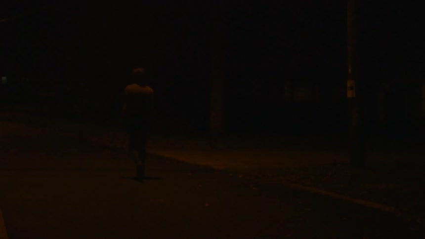 A man walks down a city sidewalk at night