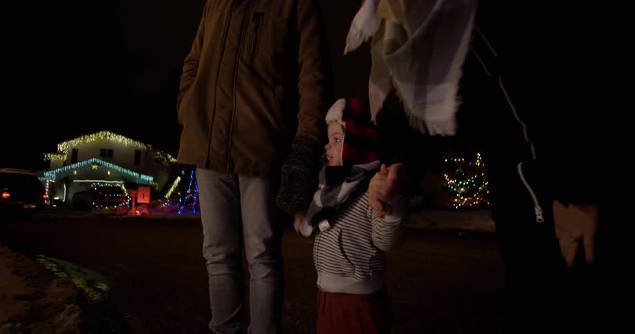 Parents hold a child's hand outside