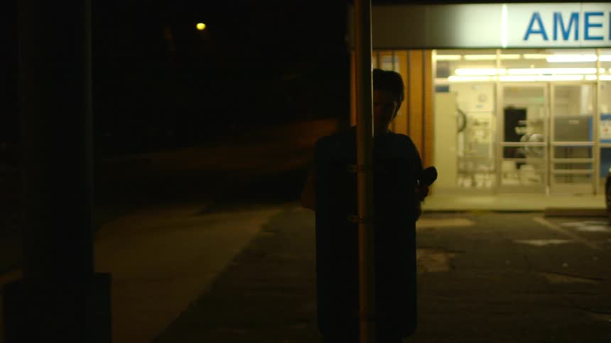 A man picks up a pay phone receiver outside a laundromat