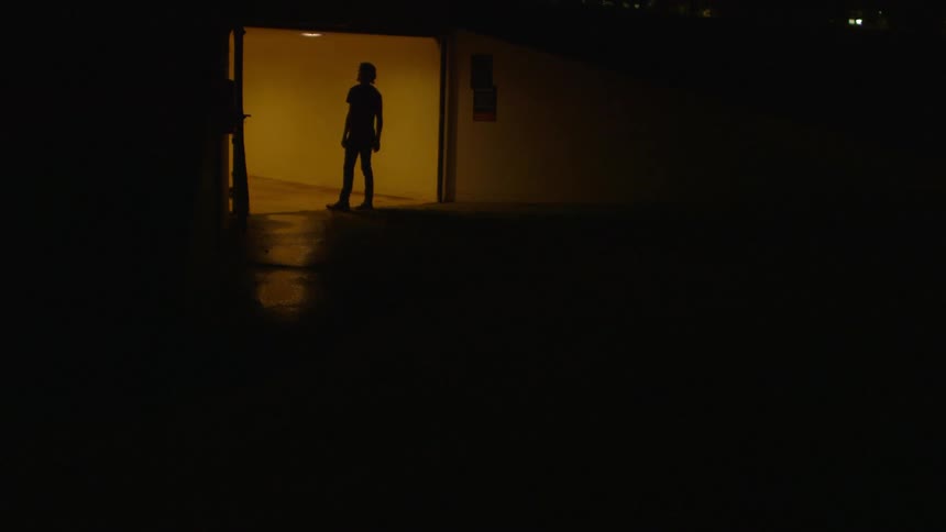A man walks into a brightly lit hallway