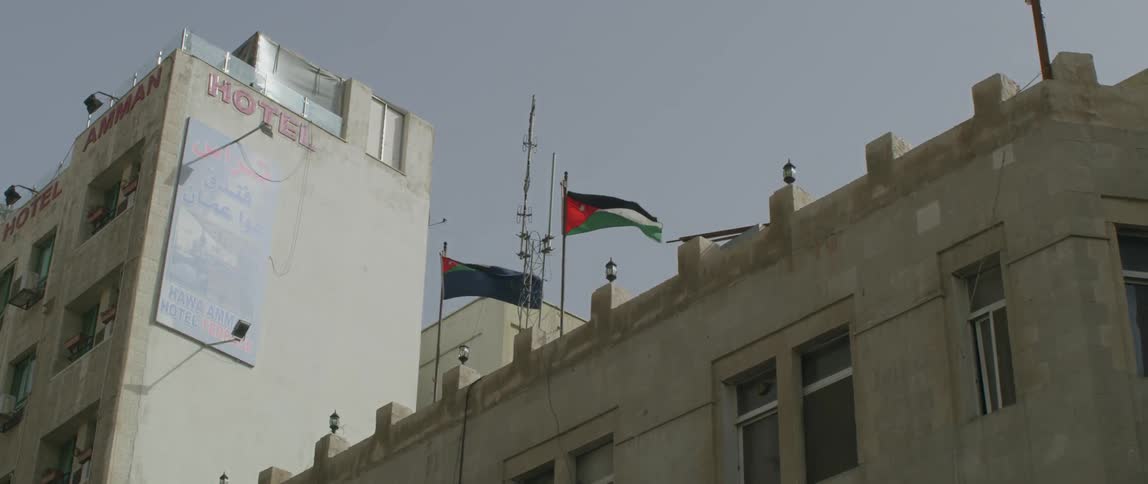 Flags fly in the breeze on top of a cement building