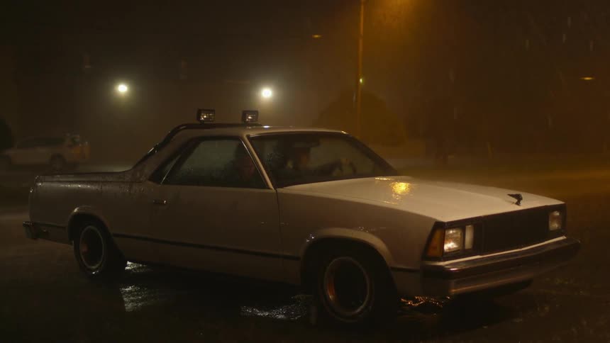 People are sitting in a car at night as it rains