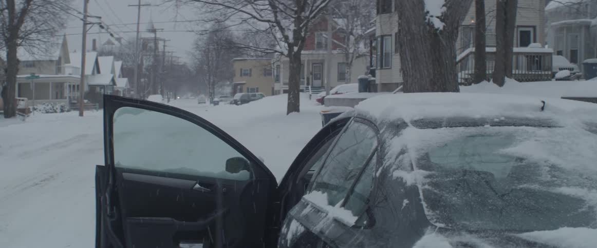 A man gets into a car on a snowy day