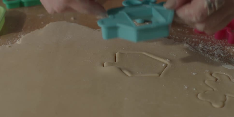 Woman uses a cookie cutter to make a dreidel in the dough