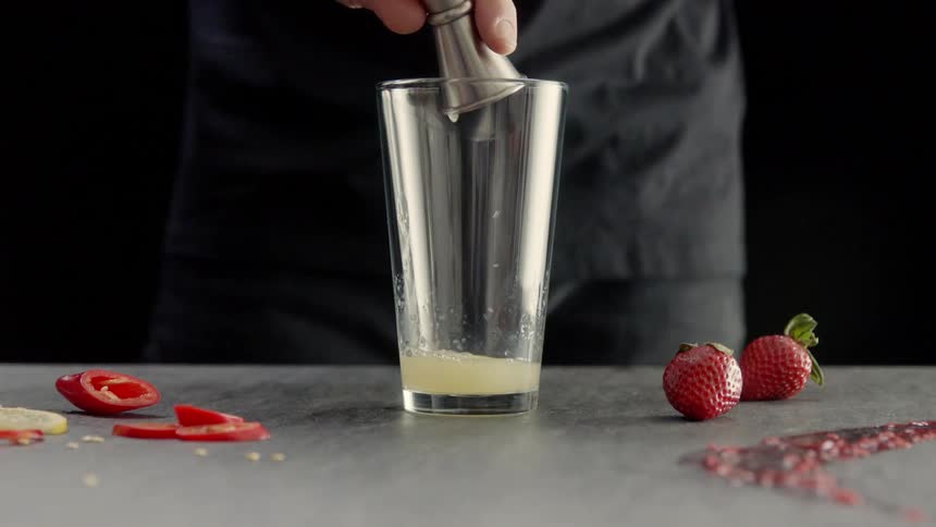 A person is mixing a drink measuring ingredients as he pours