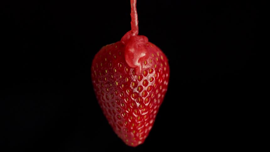 Jam is poured over a strawberry