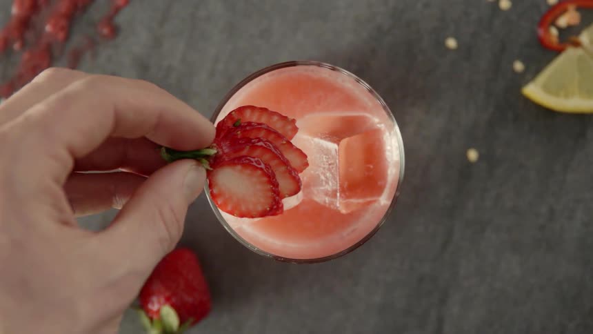 A person decorates a drink with a strawberry