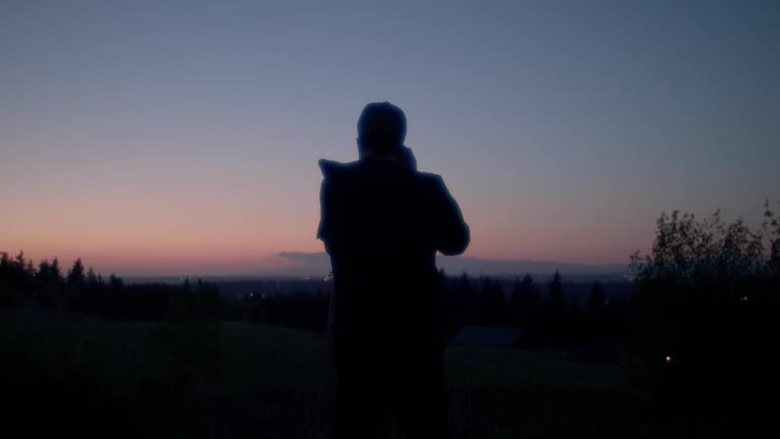 A man takes a picture of the sunset