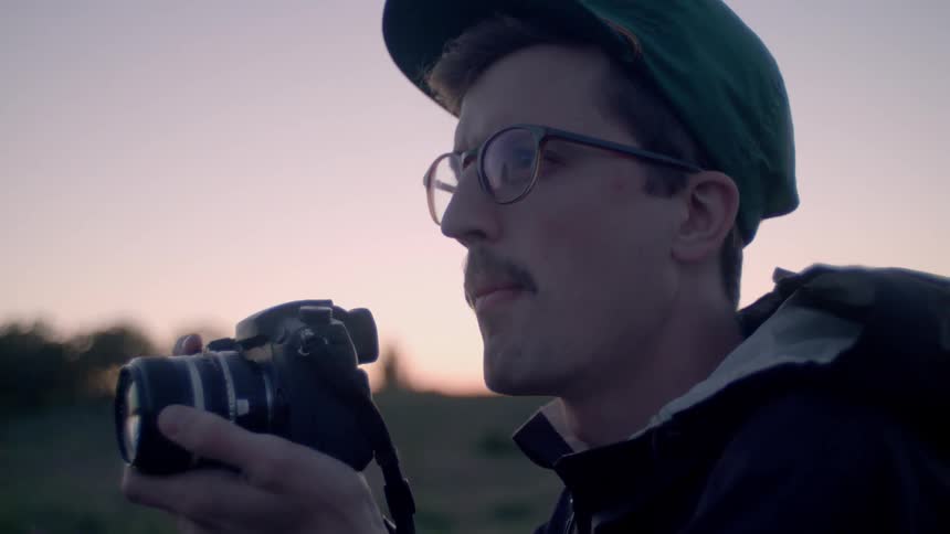 Man takes a picture outside at sunset
